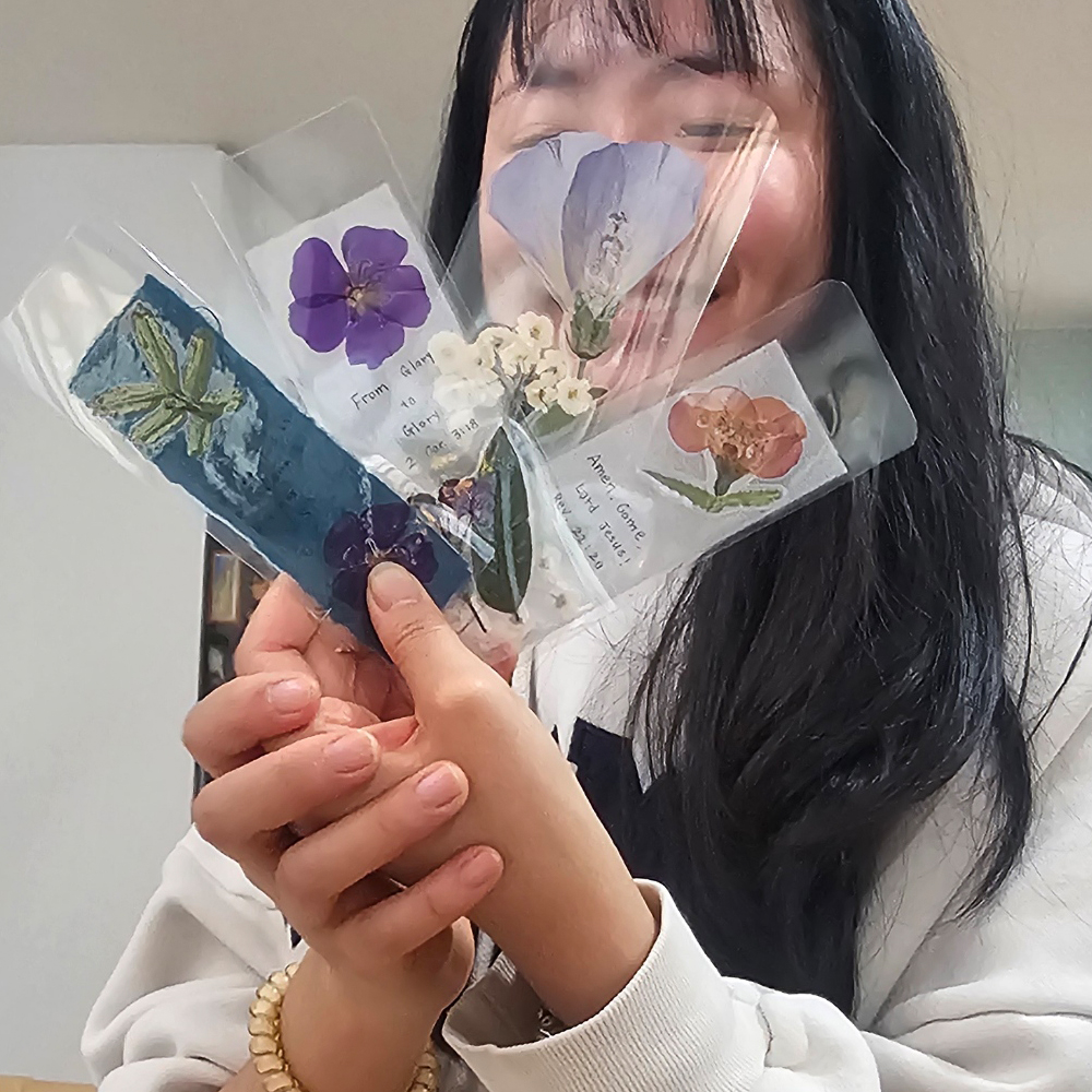 Participant fanning out laminated pressed flower bookmarks