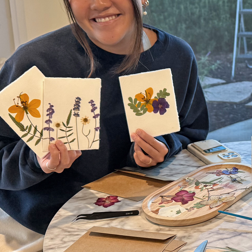 Smiling participant holding three handmade pressed flower cards