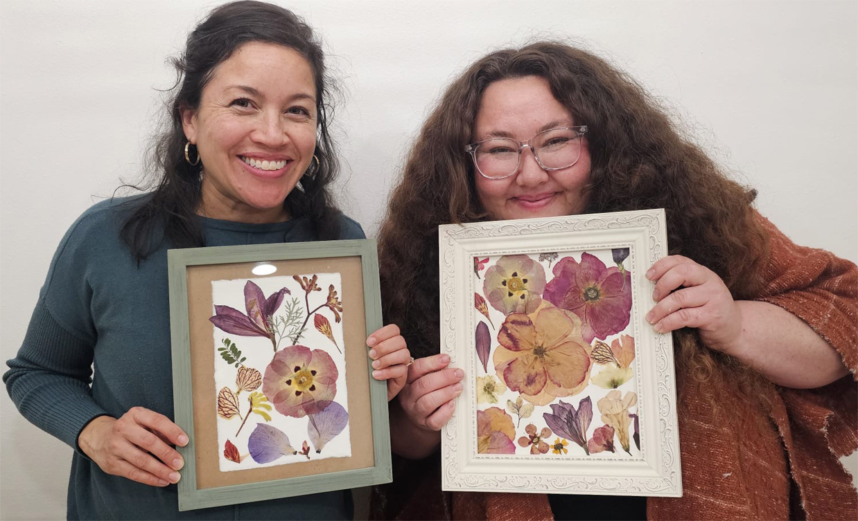Two workshop participants holding their framed pressed flower art