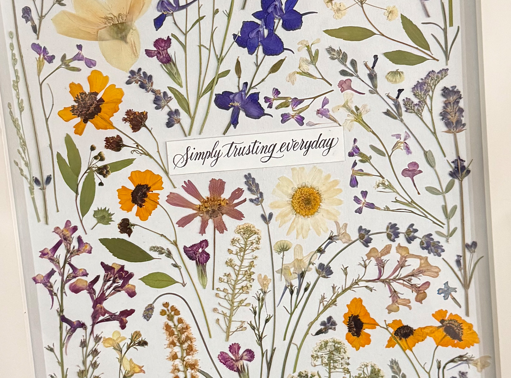Framed pressed wildflower artwork with the words Simply trusting everyday