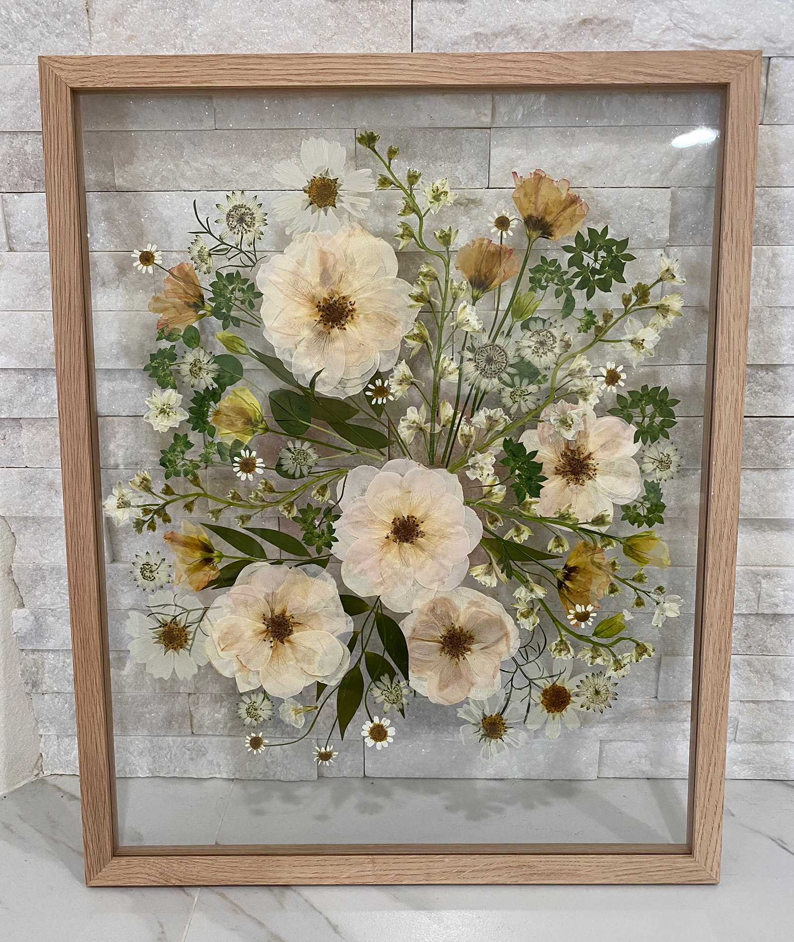 Pressed bride's bouquet of white roses floating in a glass oak frame